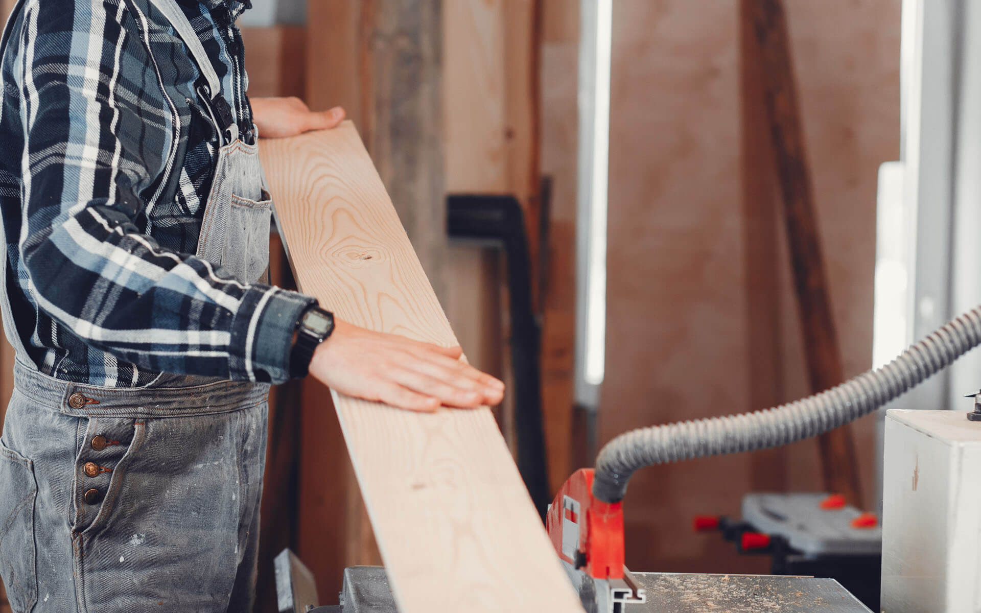 Photo of a person guiding a plank of wood onto a table saw